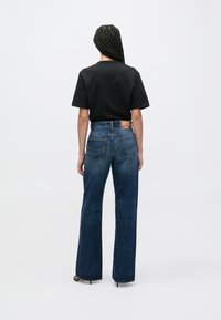 Τζιν παντελόνια από ίντιγκο ύφασμα με ψηλή μέση, φαρδιά πόδια και κλείσιμο με κουμπιά, που διαθέτουν πίσω τσέπες και πολύχρωμη ετικέτα της μάρκας στη ζώνη.