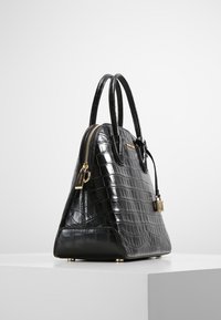 Czarna torebka ze wzorem krokodyla, z złotymi akcentami, o wykroju strukturalnym, podwójnymi uchwytami i zamknięciem na zamek. Posiada ochronne metalowe nóżki.