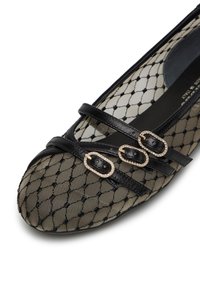 Ballerine nere in rete con cinghie incrociate e tre fibbie ovali decorate con strass. La punta ha una forma arrotondata e un motivo decorativo.