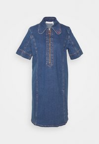 Jeansklänning med korta ärmar, spetsig krage och dragkedja framtill. Har kontrasterande sömmar och dekorativa accenter i ljusblå och röd färg.