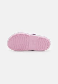 Ljust rosa gummisula med texturerade spår för grepp. Har en vit kant och ett lila band för att säkra foten.