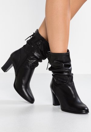 Czarne skórzane botki do kostki o luźnym fasonie, w szpic, z niskim obcasem. Posiadają boczny zamek błyskawiczny oraz subtelne przeszycia.