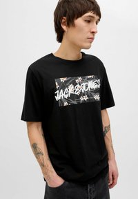 Sort bomulds T-shirt med et rektangulært blomstermotiv og "JACK & JONES" tekst. Korte ærmer, rund halsudskæring, afslappet pasform.