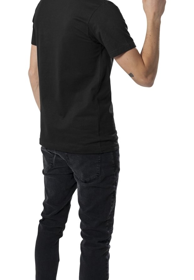 Zwarte kortemouw t-shirt van katoen, ontworpen met een ronde hals, gecombineerd met zwarte skinny jeans. De persoon is van achteren te zien.