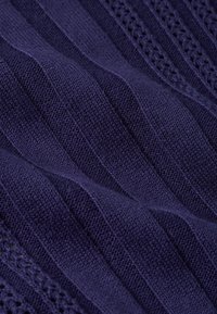 Marineblaues gestricktes Gewebe mit vertikaler Riffelstruktur, das abwechselnd glatte und strukturierte Abschnitte aufweist, die ein geschichtetes Erscheinungsbild erzeugen.