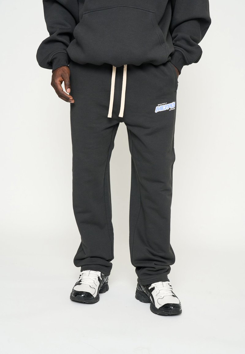 Zwarte katoenen sweatpants met een beige trekkoord, met een blauwe "MULTIPLY" logo op de linker dij en een relaxte pasvorm.