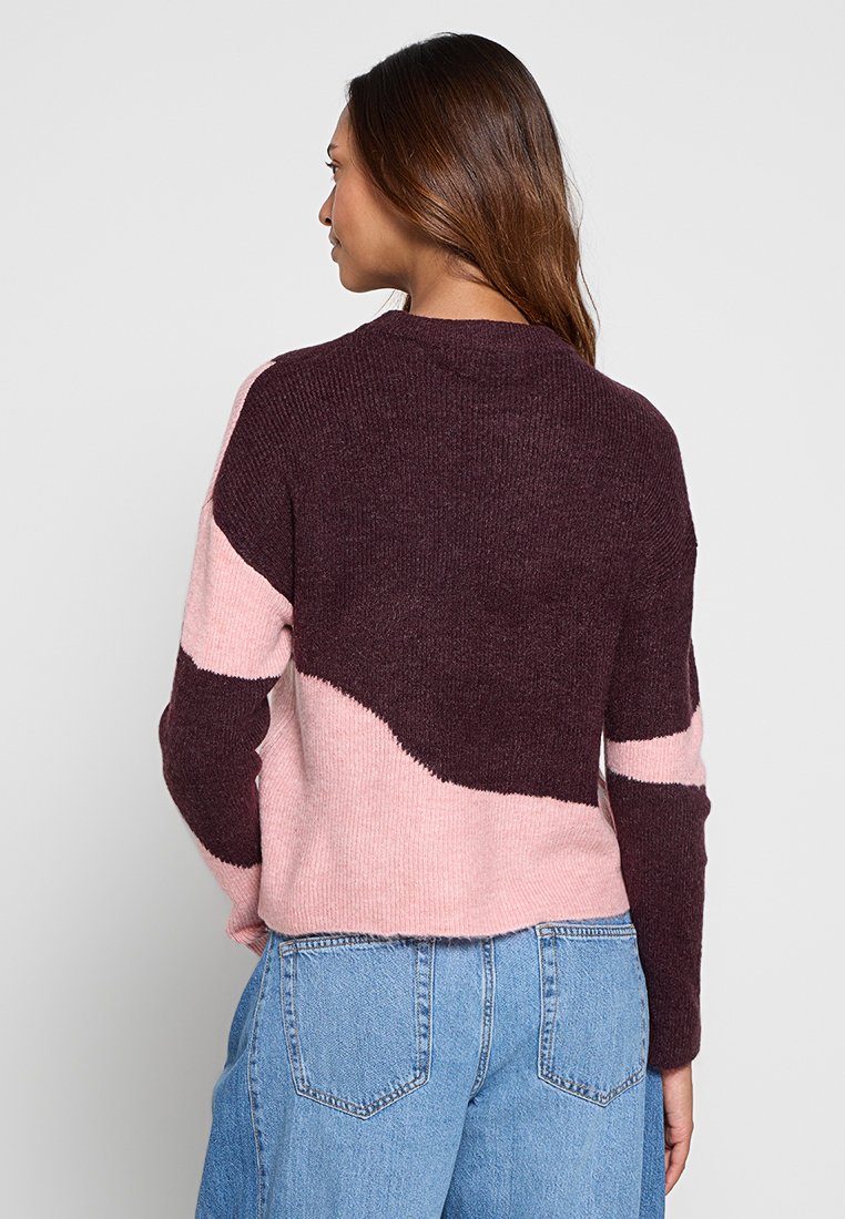 Maglione lavorato a maglia con design a blocchi di colore in burgundy scuro e rosa chiaro. Tessuto texturizzato, scollo rotondo e vestibilità corta.