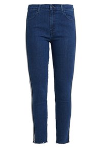 Dark blue denim jeans with a slim fit, featuring contrasting side stripes, a high waist, and a cropped hem with frayed edges.