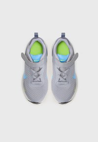 Baskets grises avec tige en mesh, accents bleus, doublure intérieure verte et semelle noire. Comprend des lacets et une sangle à Velcro.