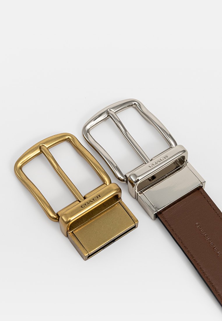 Deux boucles de ceinture : l'une dorée avec un design plat, l'autre argentée avec une forme rectangulaire et attachée à une sangle en cuir marron.