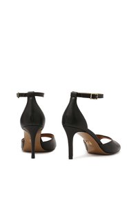 Scarpe nere in pelle con tacco alto, punta affilata, cinturino alla caviglia e sottile tacco a stiletto. Texture liscia, design minimalista.