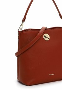 Bolso de mano de cuero rojo con una forma estructurada, que cuenta con una textura suave, una correa ajustable y un cierre circular en tono dorado.