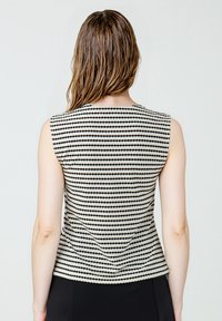 Ärmelloses Oberteil mit einem schwarzen und cremefarbenen gepunkteten Muster, glattem Stoff und einem runden Ausschnitt. Enganliegende Form mit einem leichten Stretch.