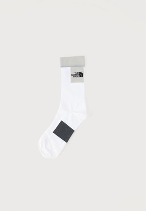White crew sock with gray cuff, black square pattern on foot, and The North Face logo near cuff on plain background.