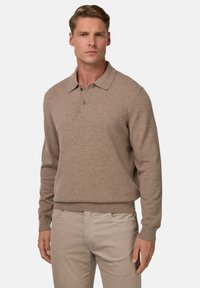 Rudas megztinis su apykakle, sagų užsegimu ir raštuotais rankogaliais bei apačia. Dėvimi su šviesios spalvos kelnių.