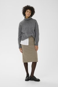 Suéter gris de cuello alto tejido, falda lápiz con patrón de pata de gallo, zapatos negros, combinado con una camisa blanca, con puños y dobladillo acanalados.