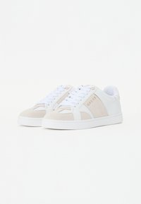 Vita sneakers med mockadetaljer i ljusbeige, platta gummisulor, rund tå och vita snören. Har "GUESS"-logotyp i guld.
