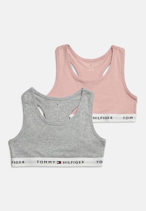 Twee Tommy Hilfiger sport-bh's, één roze en één grijs, met merkgebonden elastische banden, weergegeven tegen een witte achtergrond.