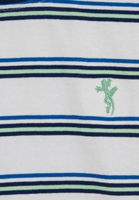 Tela blanca con rayas horizontales en azul, verde claro y azul marino, exhibiendo un pequeño lagarto verde bordado en el lado derecho.