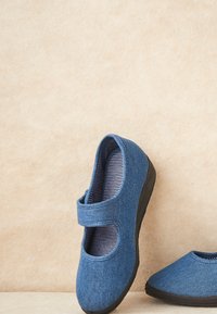 Zapatos de tela azules con punta redonda y una correa con cierre de gancho y bucle. Suelas de goma negras y forro interior a rayas.
