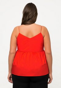 Top rosso senza maniche con design a V sul retro, vita arricciata e tessuto liscio. Presenta spalline sottili e una vestibilità morbida.
