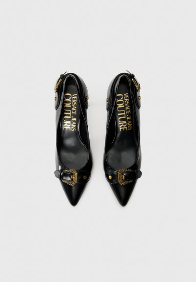 Chaussures à talons hauts en cuir noir avec des pointes effilées, présentant des accents dorés, une boucle décorative et une semelle intérieure avec une marque.