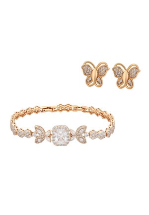 Gouden oorknopjes in de vorm van een vlinder met heldere kristalaccenten, gecombineerd met een gouden armband met een groot centraal kristal en vlindermotieven.