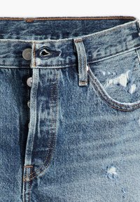 Modré džíny z denimu s vysokým pasem, pěti knoflíkovým zapínáním, opotřebovanými detaily a kontrastním šitím podél švů.