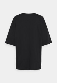 Svart oversized t-shirt med korta ärmar, rund halsringning och en mjuk bomullstextur; inga synliga mönster eller designer.