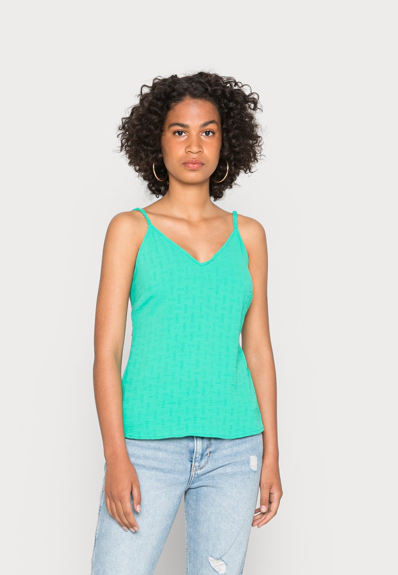 Uma blusa sem mangas em verde menta com um design em V, feita de um tecido texturizado com um padrão subtil. Leve e ajustada.