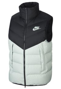 Nike ärmlös dunväst som har en svart övre sektion, ljusgrön underdel, dragkedjestängning och en framträdande Nike-logotyp på bröstet.