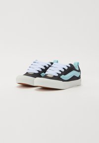 Svart og teal lærstoff sneakers med hvite lisser, rund tå, gummisåle og lyseblå detaljer på sidene og hælen.