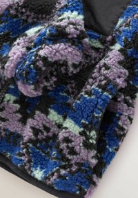 Tissu en polaire à texture douce avec un motif abstrait coloré dans des nuances de bleu, violet, noir et vert clair.