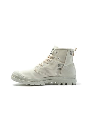 Bottine blanche en toile avec une semelle en caoutchouc texturée, dotée de lacets beige clair et d'un logo sur le côté. Accents de design écologique.