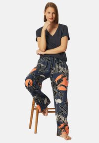 Comodo top scuro a scollo a V abbinato a pantaloni navy con stampa floreale e accenti arancioni. Tessuto morbido, vestibilità rilassata e vita elasticizzata.