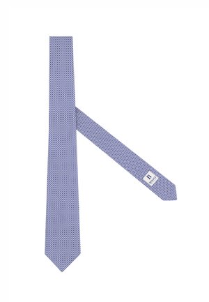 Niebieski krawat z wzorem w małe powtarzające się koła, z białą metką z nazwą marki na węższym końcu.