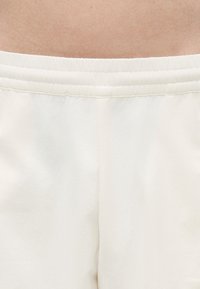 Μεσότητα και ανώτερο τμήμα λευκού ελαστικού ζώνη μακριών παντελονιών σε πρόσωπο με ορατό δέρμα πάνω από τη μέση.