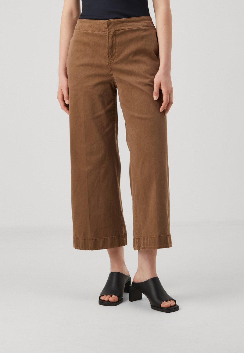 Brune vide benbukser laget av bomull, med en jevn tekstur, frontlommer og cropped hem. Kombinert med svarte blokk hæl mules.