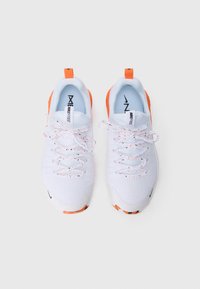 Tênis atléticos brancos com detalhes laranja, cadarços brancos salpicados e marca Nike Free, vistos de cima contra um fundo branco.