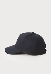 Marineblå baseballkasket med buet skygge, lavet af tekstureret stof, med et broderet logo foran og en justerbar rem bagpå.