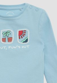 Lichtblauw long-sleeve shirt met geborduurde palmbomen en zon graphics, met daaronder de tekst "Buiten, het plezier is begonnen". Knopdetails op de schouder.