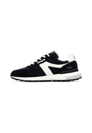 Zapatillas deportivas en blanco y negro con parte superior de ante, suela de goma texturizada, cordones y un diseño de rayas en contraste.