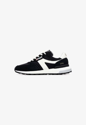 Zapatillas deportivas en blanco y negro con parte superior de ante, suela de goma texturizada, cordones y un diseño de rayas en contraste.
