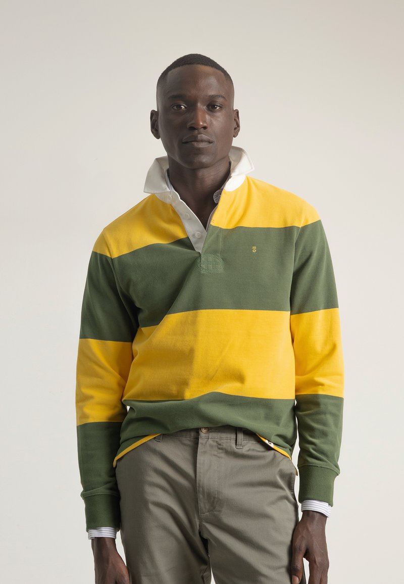 Camisa polo de manga larga con franjas horizontales en amarillo y verde, cuello con solapa y forro interior blanco, y detalle texturizado en la parte delantera.