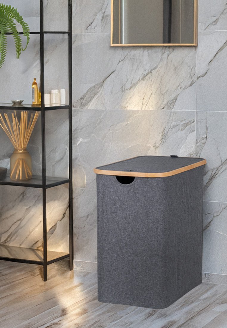 Grijze stoffen wasmand met een gladde houten deksel en uitsparing voor een handvat. Rechthoekige vorm en gestructureerd materiaal tegen een marmeren achtergrond.