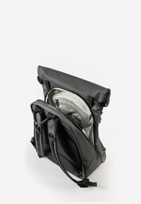 Zaino impermeabile grigio con chiusura roll-top, spallacci regolabili e un interno spazioso di colore chiaro con tasca con zip.