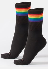 Calcetines negros con rayas de arcoíris en relieve en la parte superior. Textura suave, diseño de altura de tobillo, área de los dedos del pie acolchada, acentos en contraste en el talón.