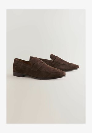 Braune Wildleder Slipper mit glatter Oberfläche, ausgestattet mit einem dekorativen Riemen und gestickten Details, ergänzt durch einen flachen Absatz.