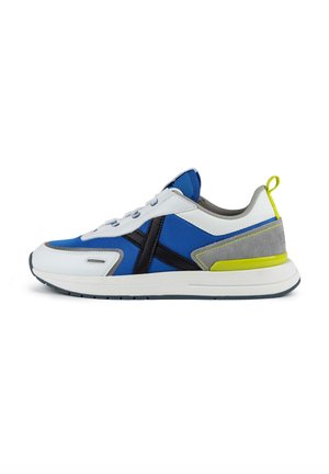 Chaussure de sport bleue et blanche avec des accents noirs, un talon en suède gris et un onglet de talon jaune fluo. Elle présente des éléments en tissu texturé et en cuir lisse.