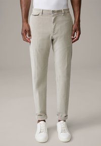 Pantalon en velours côtelé beige clair à coupe droite, poches avant, fermeture par boutons, revers roulés, associé à des baskets blanches. Texture lisse.